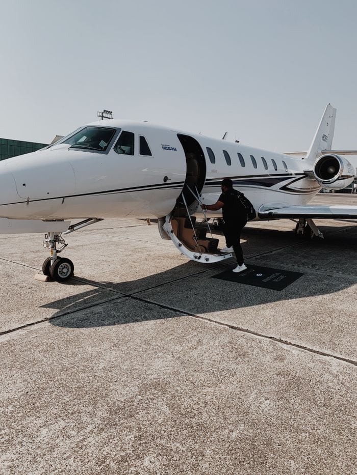 our-story Person boarding a private jet at an airport in Guatemala City on a sunny day.